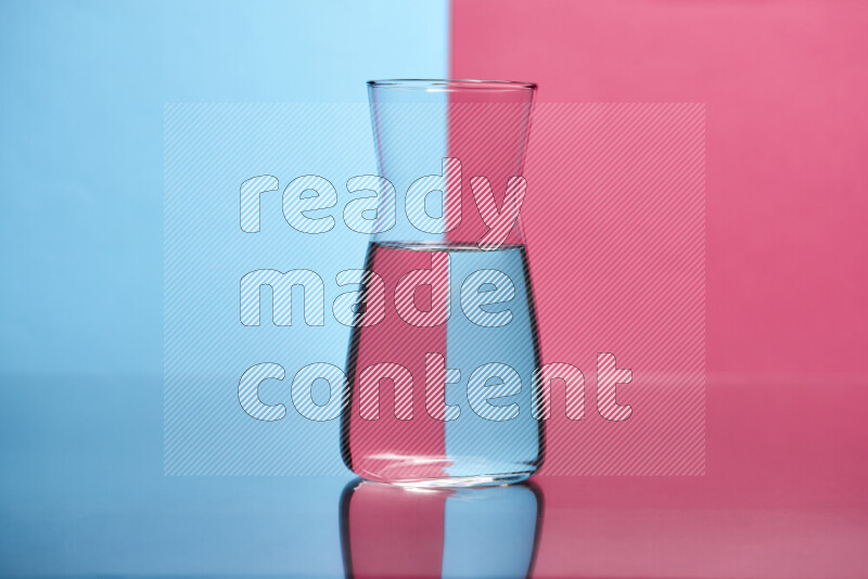 The image features a clear glassware filled with water, set against light blue and pink background