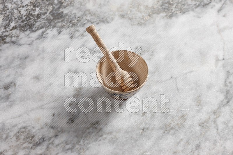 Decorative Pottery Bowl with wooden honey handle in it, on grey marble flooring, 65 degree angle