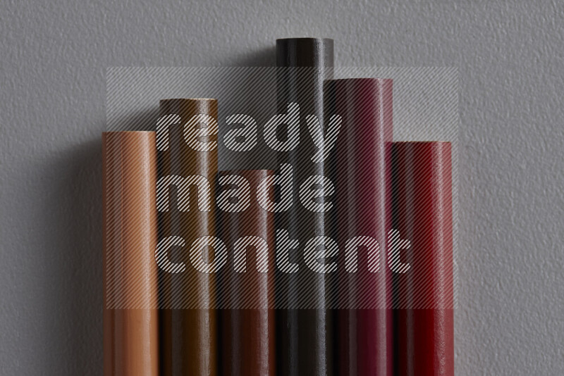 A collection of colored pencils arranged showcasing a gradient of brown hues on grey background
