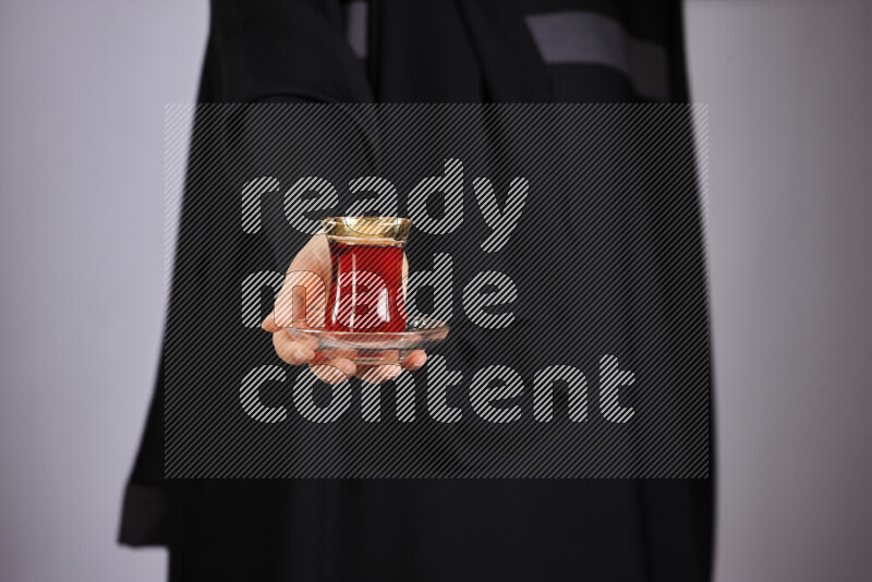 A woman in black abaya holding different glassware in different positions