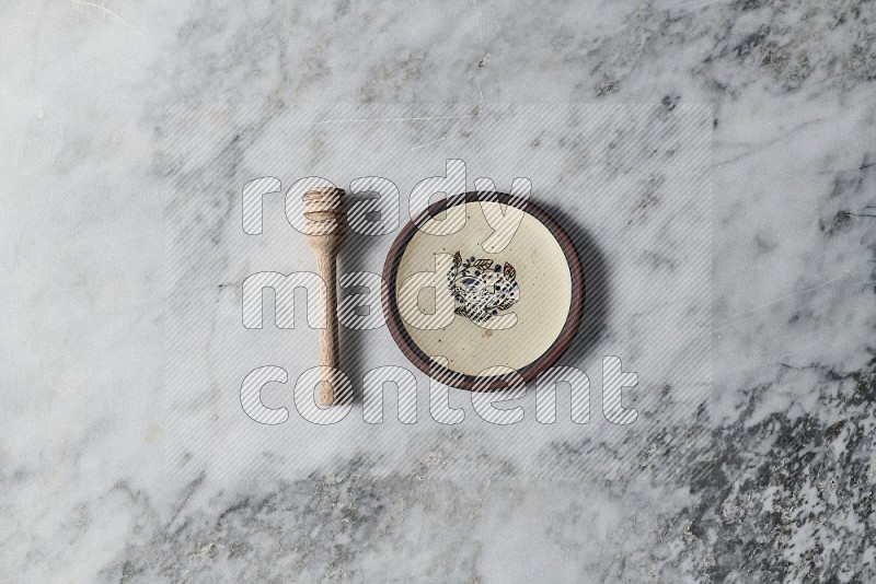 Decorative Pottery Plate with wooden honey handle on the side on grey marble flooring, Top view