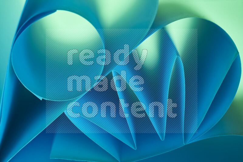 عرض فني لطيات الورق تخلق مزيج من الأشكال الهندسية، مضاءة بإضاءة ناعمة بدرجات اللون الأخضر والأزرق