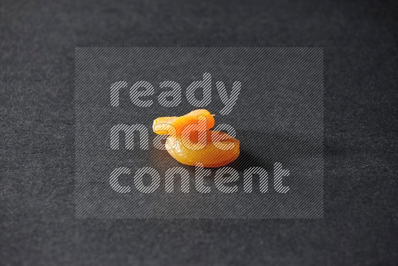 Two dried apricots on a black background in different angles