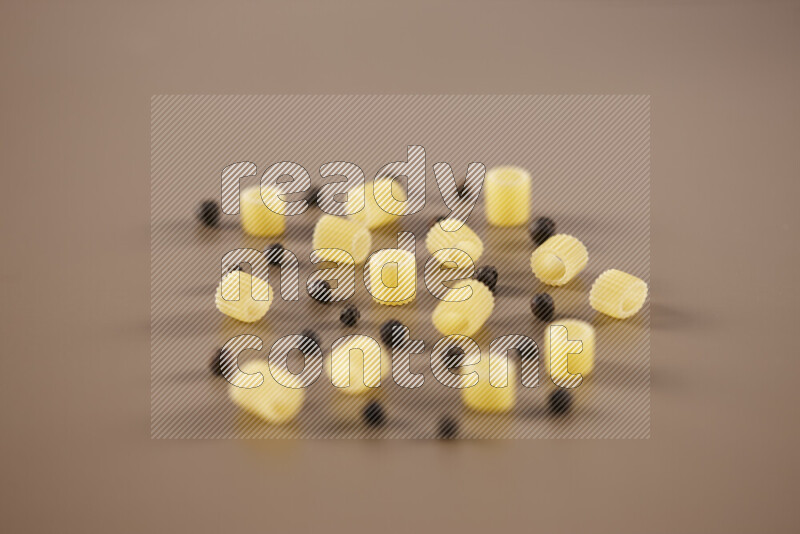 معكرونة مع مكونات متنوعة من الطماطم والثوم والبصل والفلفل الأحمر والفلفل الأسود والفلفل الأبيض وأوراق الغار وإكليل الجبل والهيل على خلفية بيج