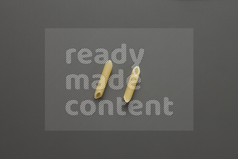 Mini penne pasta on grey background