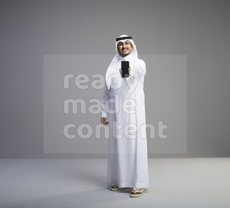 رجل سعودي يرتدي ثوب وشماغ يحمل جوال
