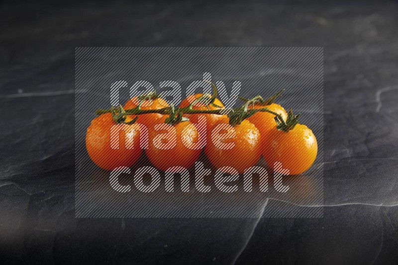 Orange cherry tomato vein on a textured black slate background 45 degree