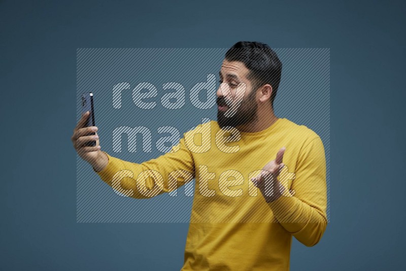 Man Taking a Selfie  in a blue background wearing a yellow shirt