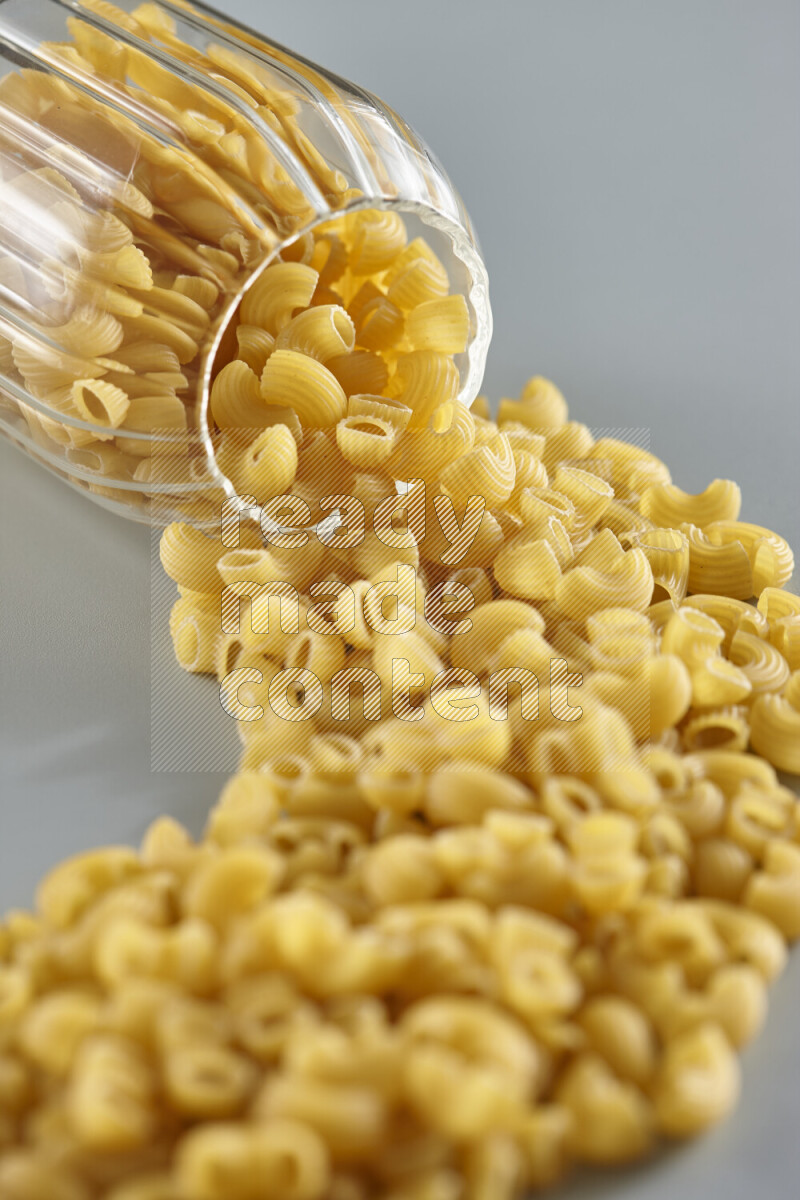 Flipped jar full of raw pasta on light blue background