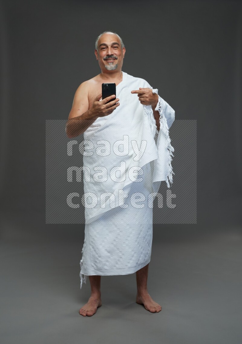 A man wearing Ehram Standing taking selfie on gray background