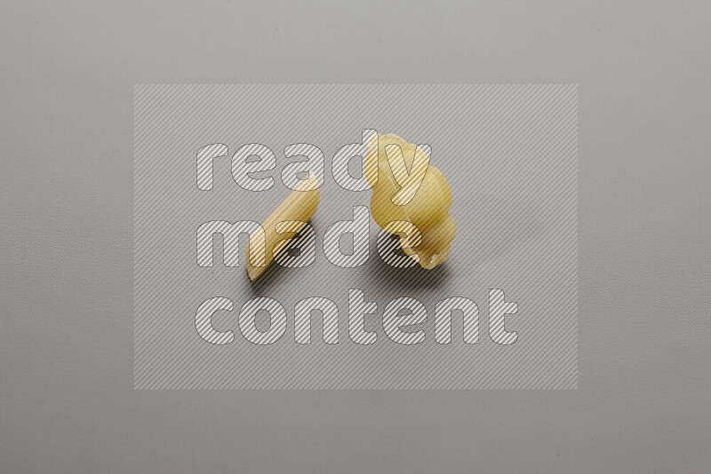 Mini penne pasta with other types of pasta on grey background