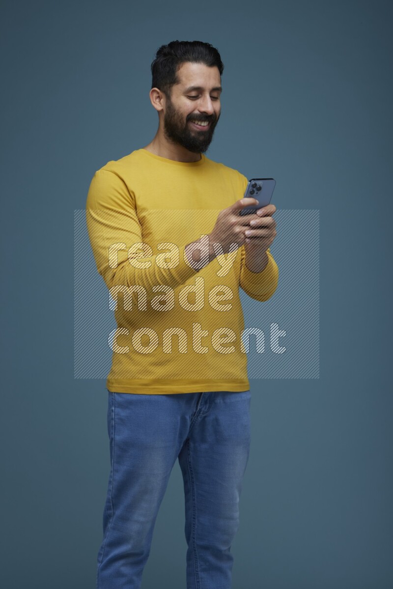 Man typing on his phone in a blue background wearing a yellow shirt