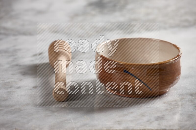 Multicolored pottery bowl with wooden honey dipper on the side on grey marble background