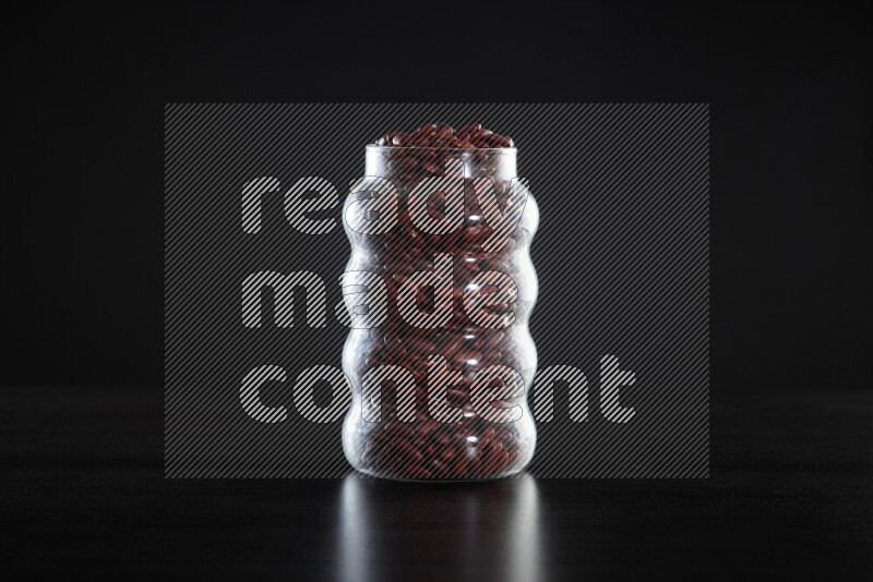 Red kidney beans in a glass jar on black background