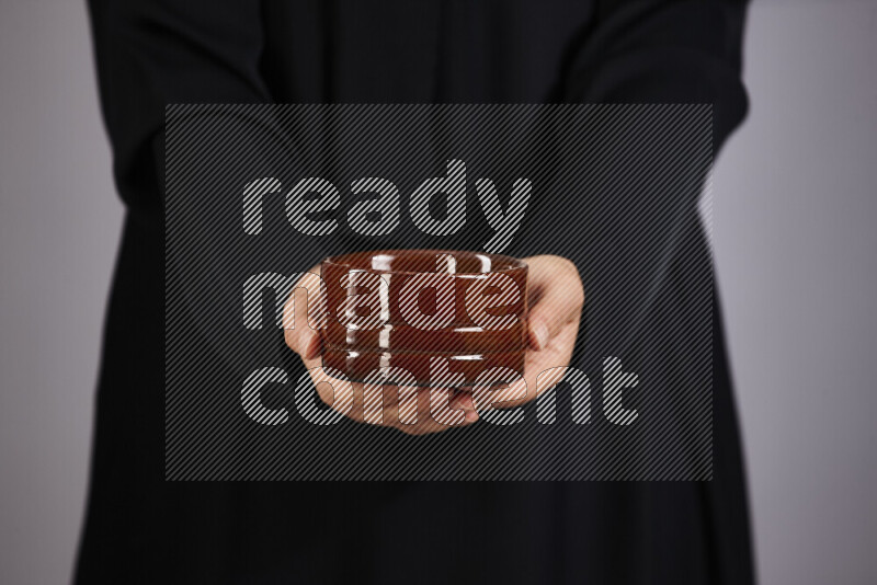 A woman in black abaya holding different pottery essentials in different positions