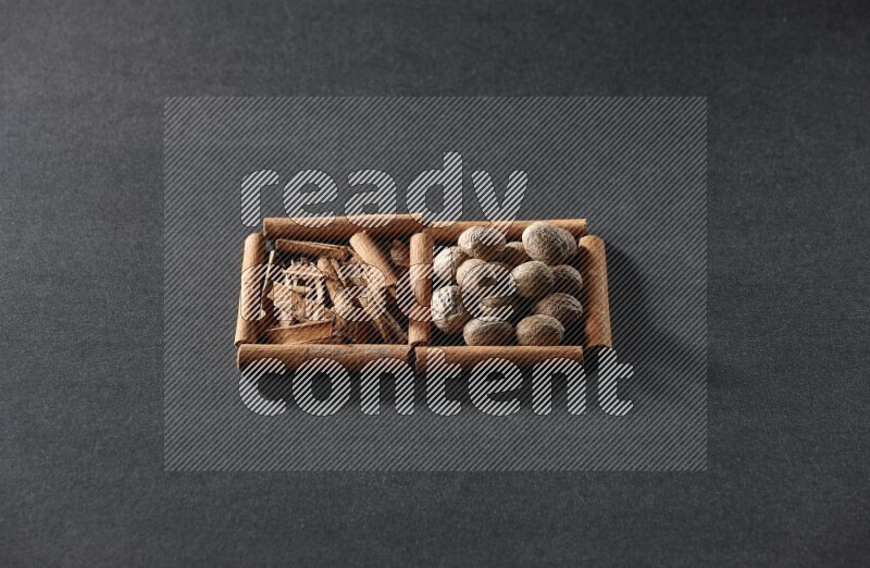 2 squares of cinnamon sticks full of cinnamon and nutmeg on black flooring