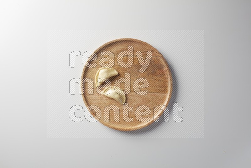 Two Sambosas on a wooden round plate on a white background