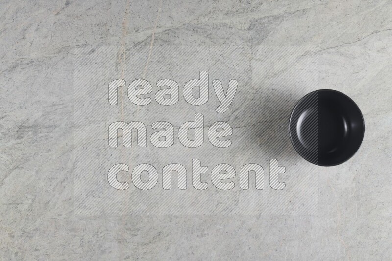 A black ceramic bowl on grey marble background