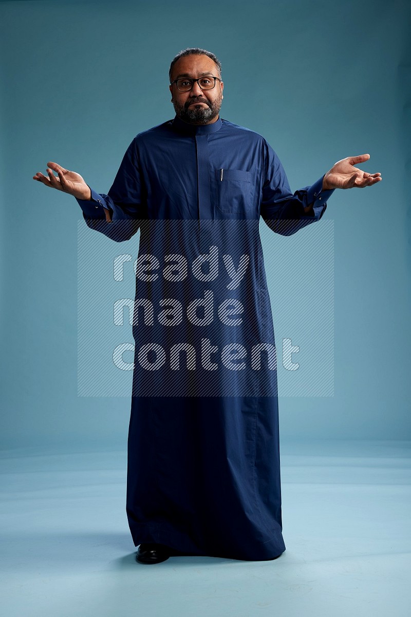 Saudi Man without shimag Standing Interacting with the camera on blue background