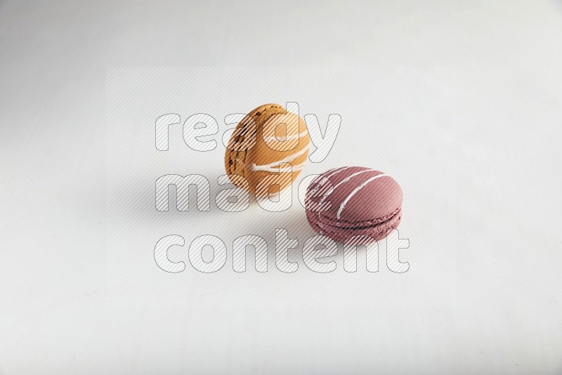 45º Shot of of two assorted Brown Irish Cream, and Red Poppy Flower macarons on white background