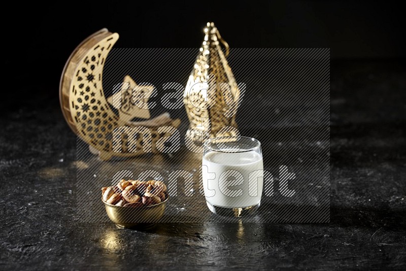 Nuts in a metal bowl with milk beside golden lanterns in a dark setup