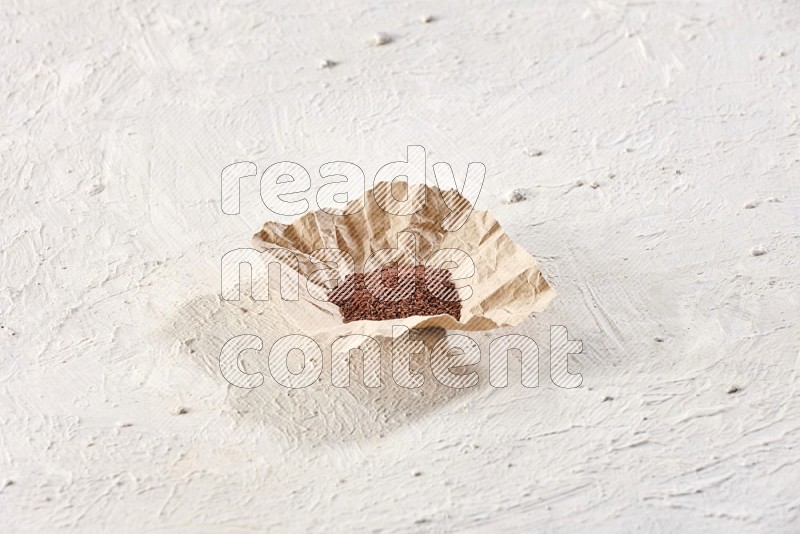 A crumpled piece of paper full of garden cress on a textured white flooring in different angles