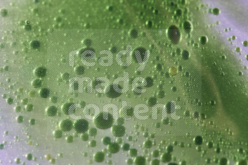 Close-ups of abstract green watercolor drops on oil Surface on white background