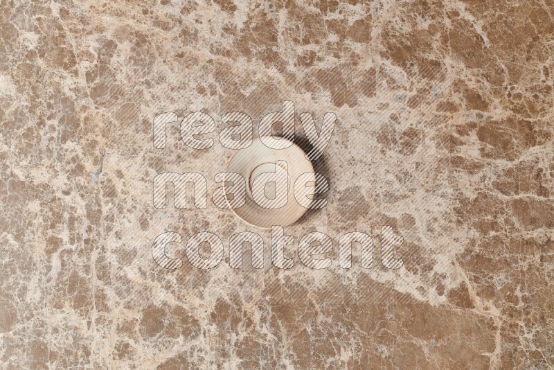 A beige pottery plate on beige marble background