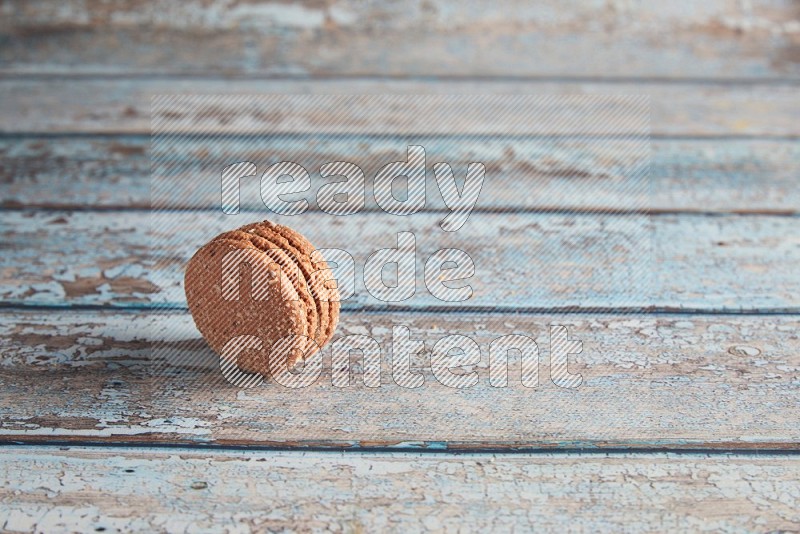 45º Shot of Brown Hazelnuts macaron on light blue wooden background