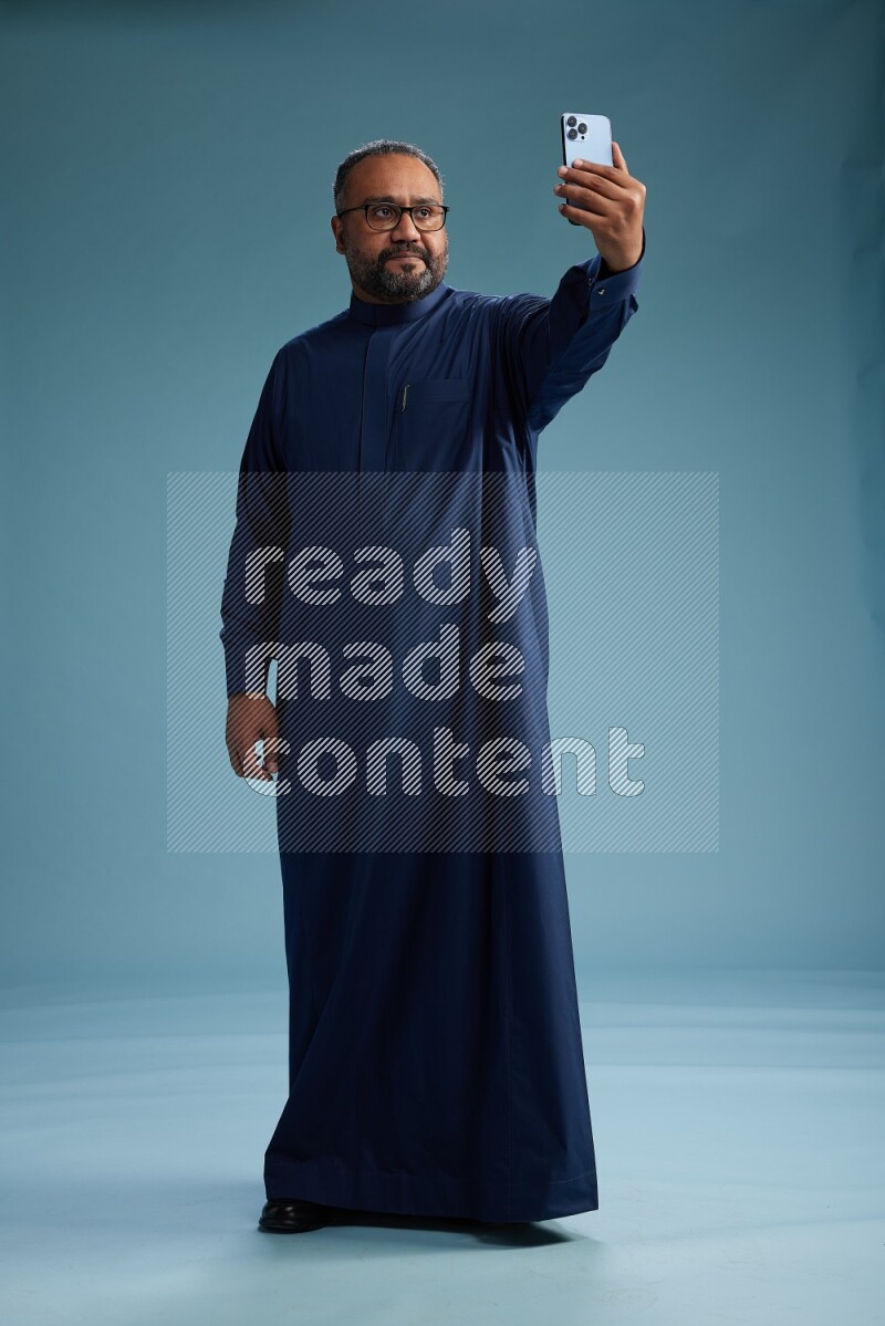Saudi Man without shimag Standing taking selfie on blue background