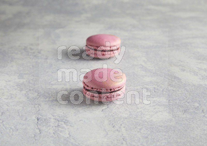 45º Shot of two Purple Strawberry macarons on white  marble background