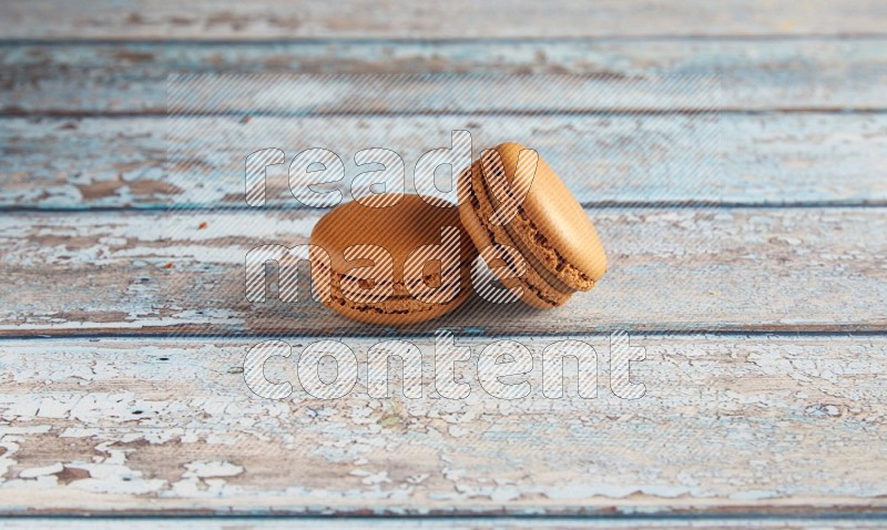 45º Shot of two Brown Maple Taffy macarons on light blue wooden background