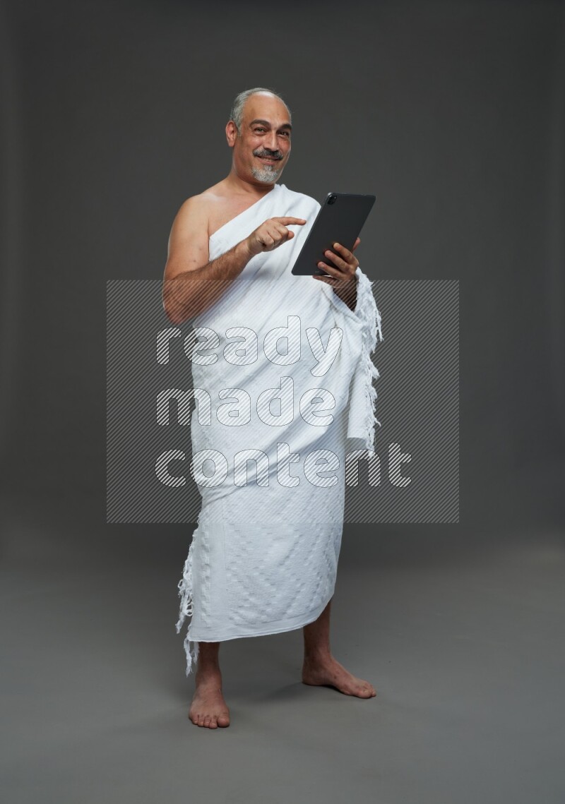 A man wearing Ehram Standing working on tablet on gray background