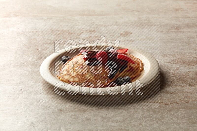 Three stacked mixed berries pancakes in a grey plate on beige background