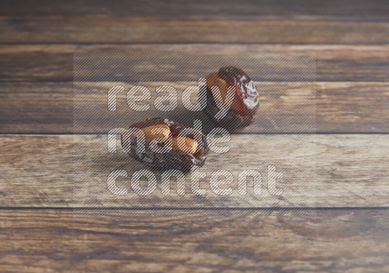 two almond stuffed madjoul dates on a wooden background
