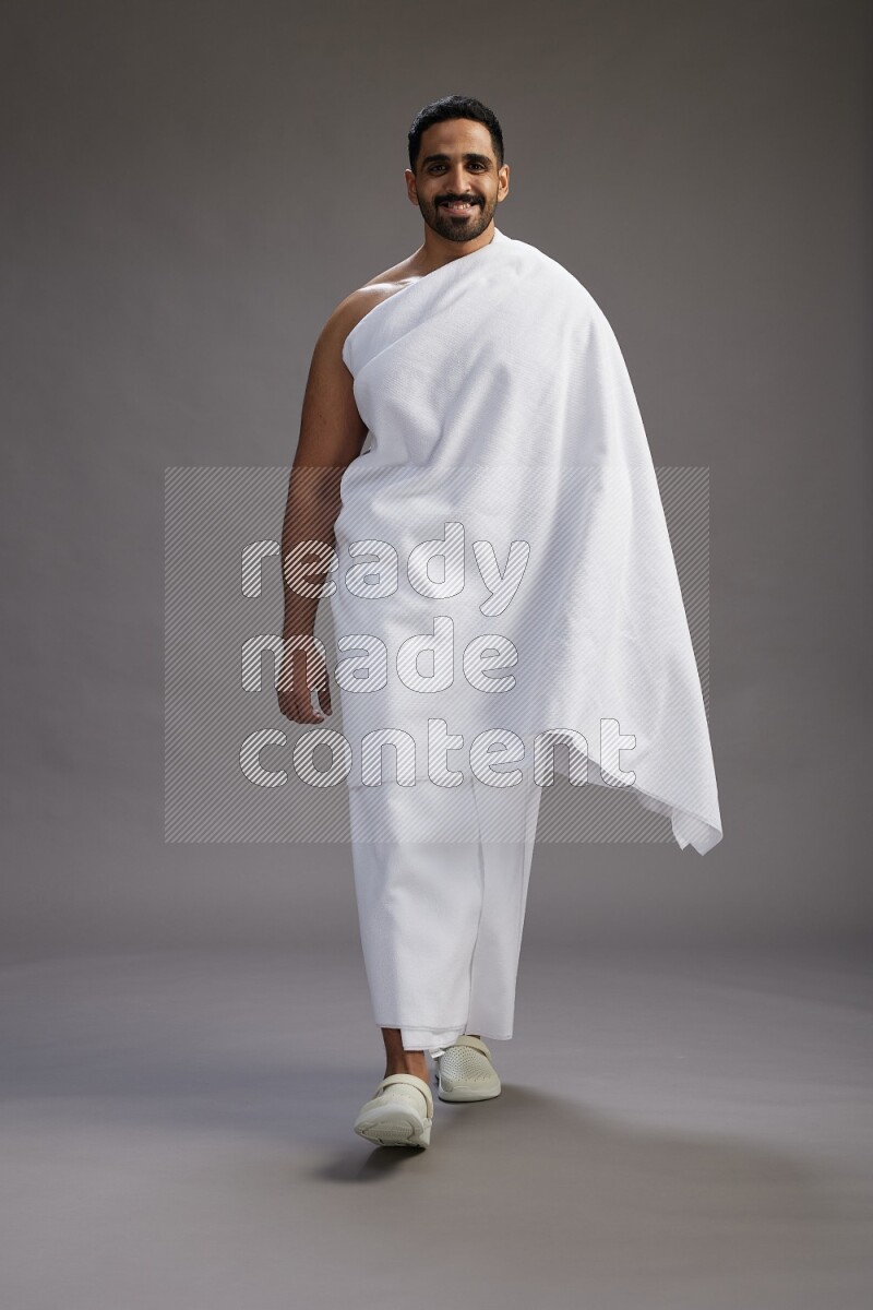 A man wearing Ehram Standing Interacting with the camera on gray background