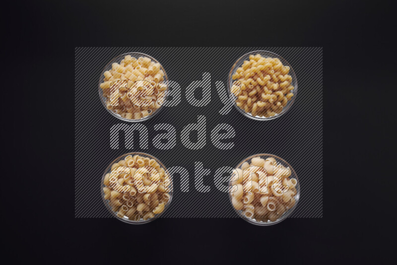 أنواع مختلفة من المعكرونة في وعاء زجاجي علي خلفية سوداء