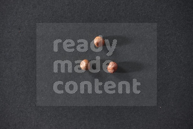 3 peeled hazelnuts on a black background in different angles