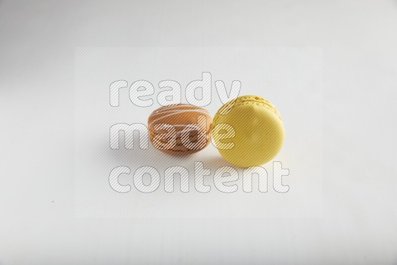 45º Shot of of two assorted Brown Irish Cream, and Yellow Lemon macarons on white background