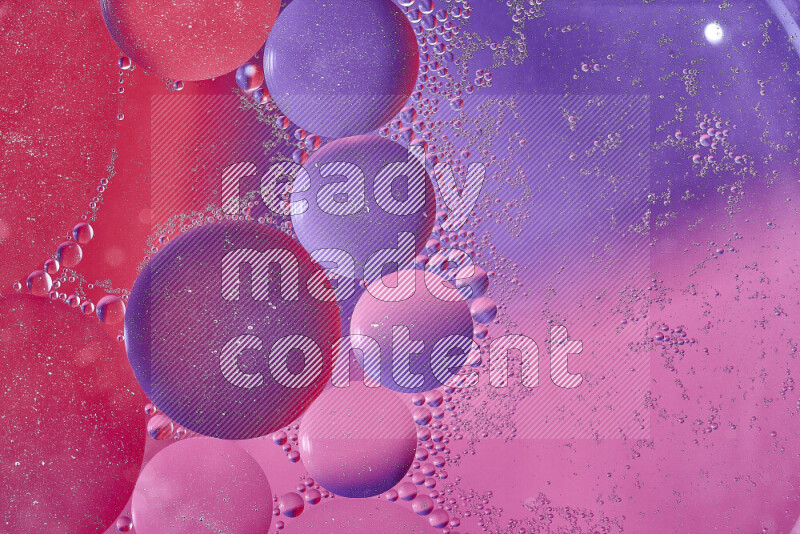 Close-ups of abstract oil bubbles on water surface in shades of red, purple and pink