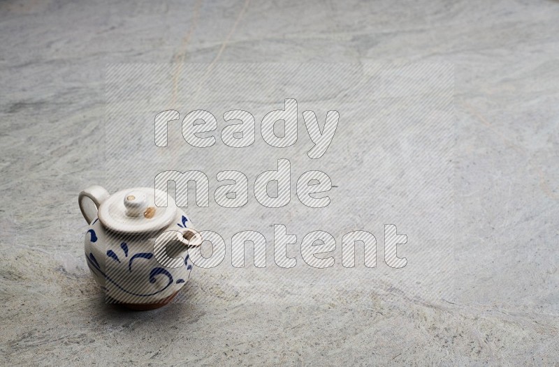 A Pottery Teapot On Grey Marble Flooring