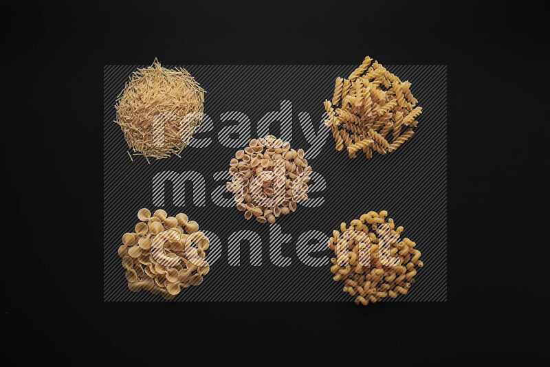 Different pasta types in bunches on black background