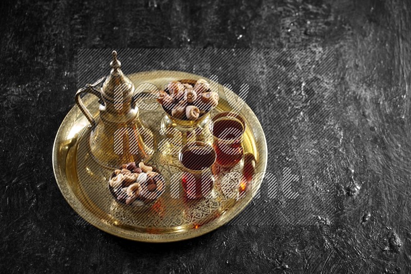 Nuts with dates and a drink on a metal tray in a dark setup