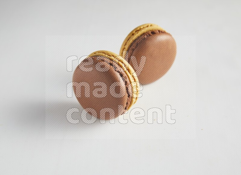 45º Shot of two Yellow and Brown Chai Latte macarons on white background