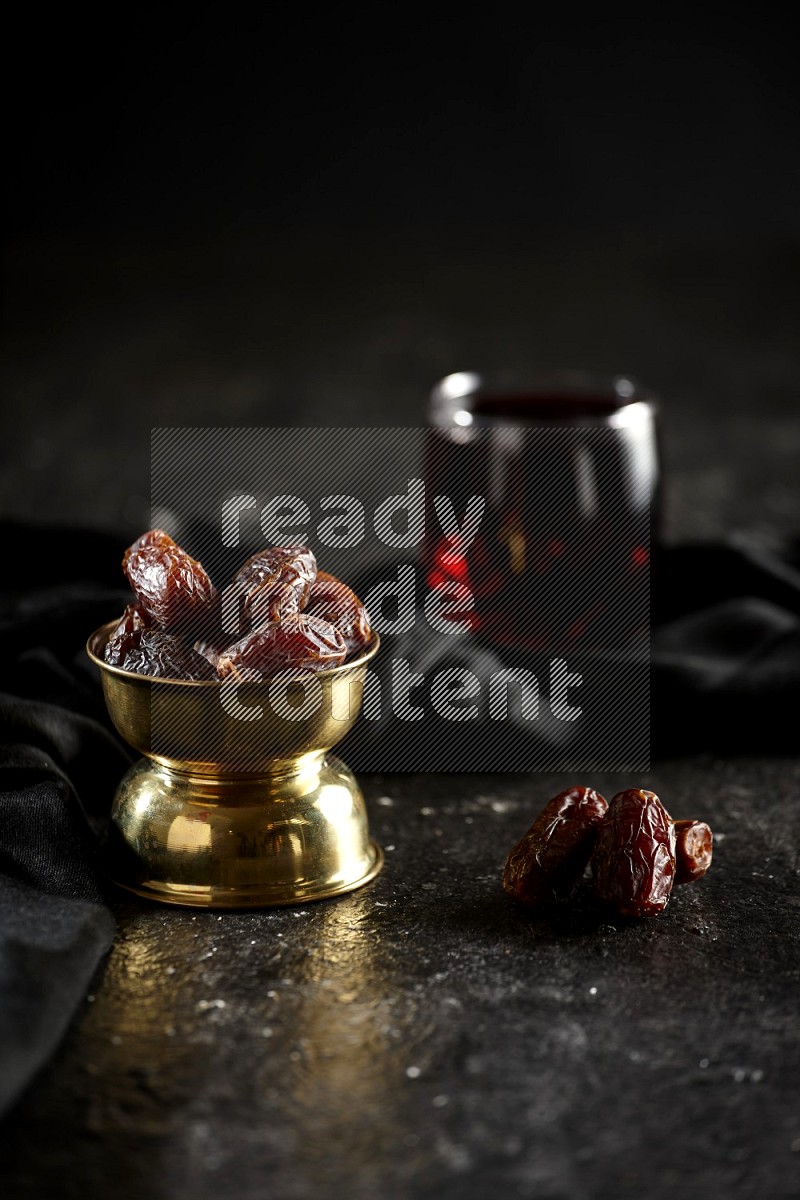 Dried fruits in a metal bowl with Hibiscus and a napkin in a dark setup