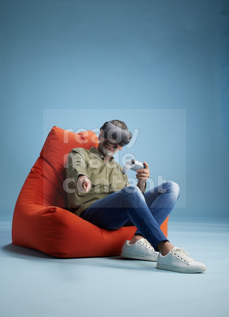 A man sitting on an orange beanbag and gaming with VR