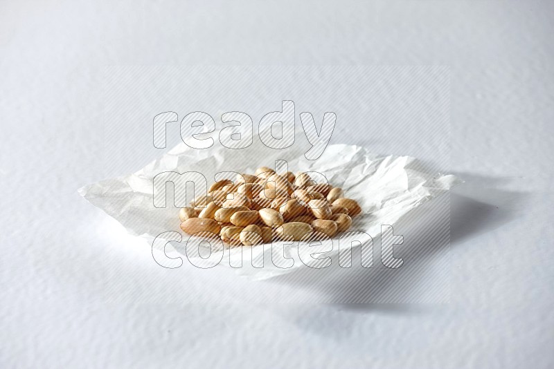 Peeled peanuts on a crumpled piece of paper on a white background in different angles