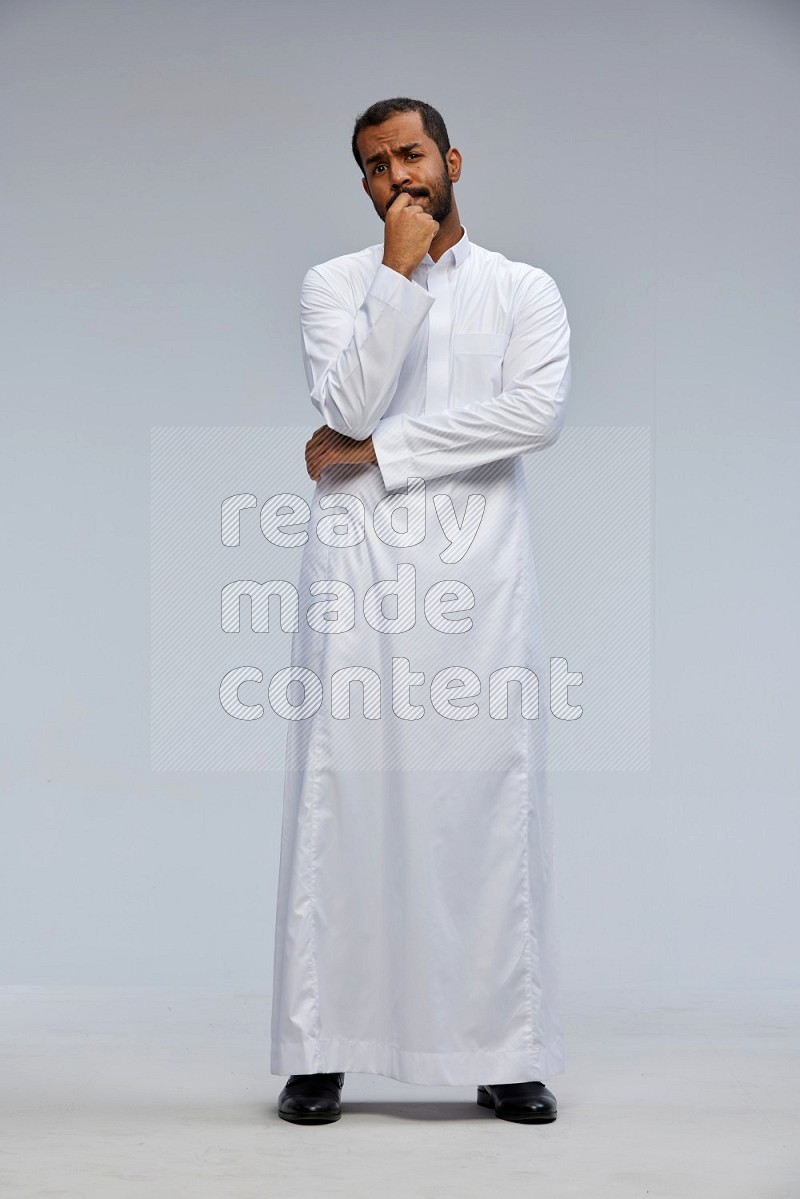 Saudi man Wearing Thob standing interacting with the camera on Gray background