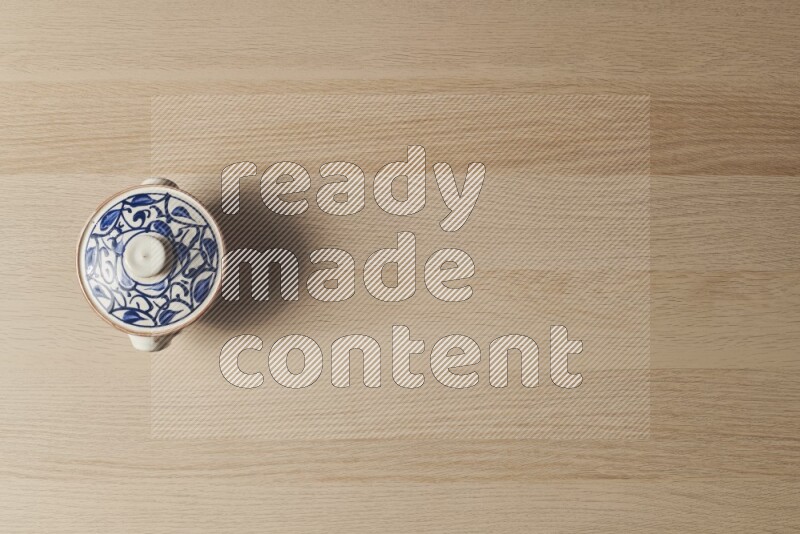 إناء فخاري متعدد الألوان على خلفية خشبية فاتحة