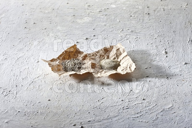 حبوب وبودرة الفلفل الأبيض في قطع من الورق على أرضية بيضاء